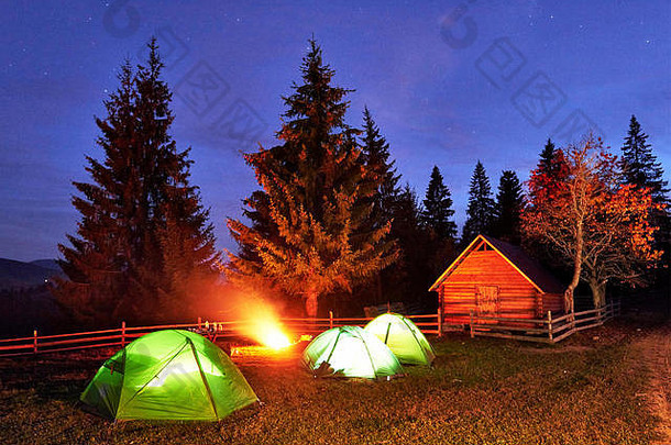 夜间露营。游客们在明亮的帐篷和木屋附近的篝火旁休息，在布满星星和银河的令人惊叹的夜空<strong>下</strong>。天体摄影