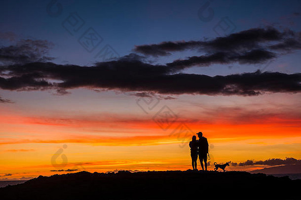 浪漫的夫妇wioth狗享受日落红色的橙色彩色云天空旅游热旅行概念快乐了吗