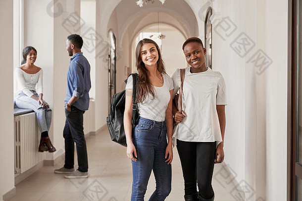 非洲和高加索人女学生在走廊上休息，对着摄像机微笑。美女交友，留学国际大学。国际友谊的概念。