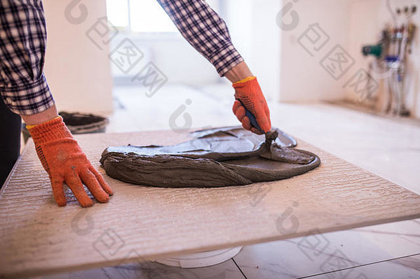 家装、装修施工工人正在铺瓷砖、瓷砖地板粘合剂