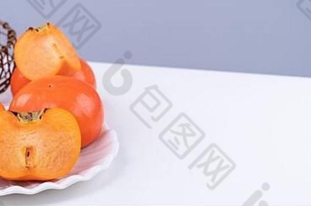 新鲜美丽的甜柿片，独立于灰蓝色背景的白色厨房餐桌上，中国农历新年设计理念，特写