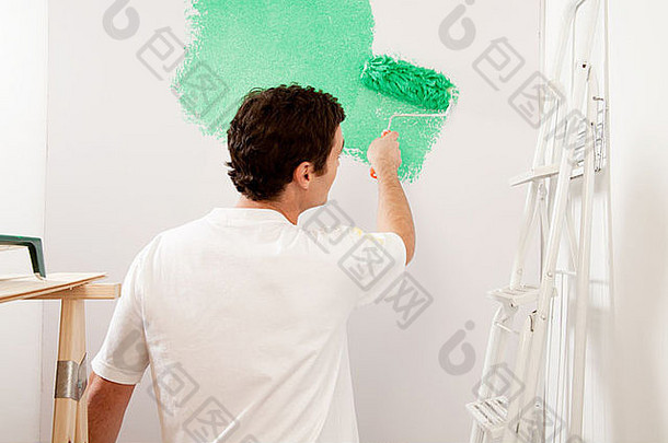 一个没有脸的男人用滚筒刷在墙上画画，家庭装修