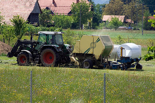 拖拉机用机器收集和包装干草。