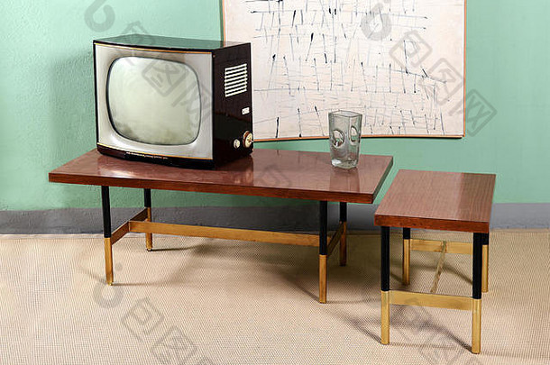 带有家具的复古客厅依然栩栩如生——桌子上放着旧电视，绿色房间里有玻璃花瓶，抽象的墙面艺术和米色地毯