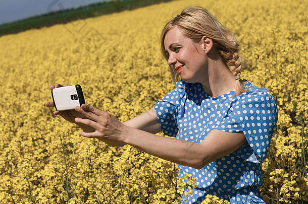 一位金发女郎在黄色油菜花圃里自拍的水平照片