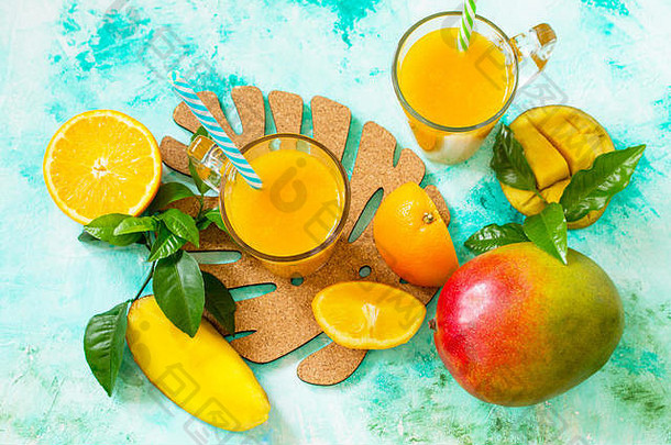 清新的夏季芒果和柑橘鲜榨果汁。素食概念，新鲜维生素。俯视平面背景。