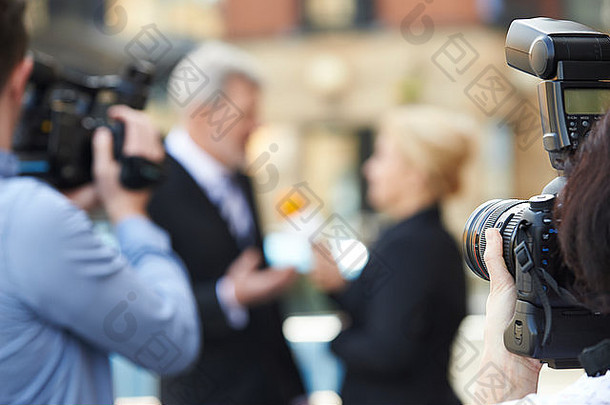 摄影师拍摄女记者采访商人的照片