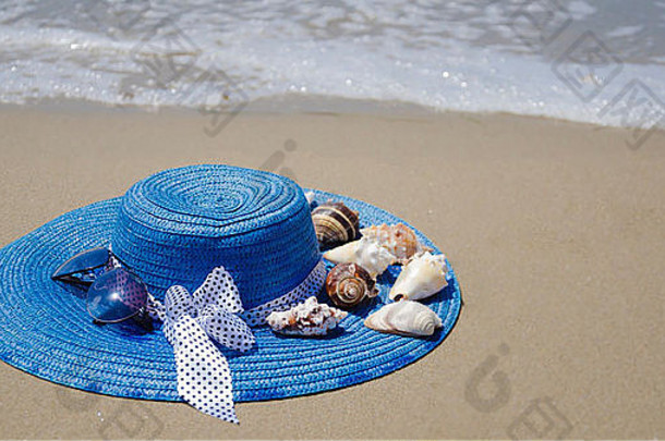 海滩沙滩上有贝壳的蓝色夏日女帽