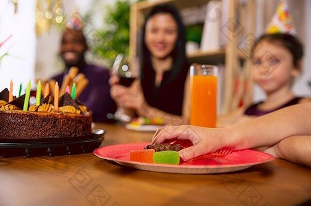 家人在家庆祝生日时，用糖果拍下手的特写镜头。一个大家庭一边吃蛋糕，一边喝酒，一边打招呼，一边玩孩子。庆祝、家庭、聚会、家庭概念。