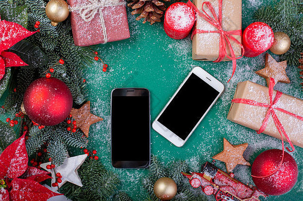 圣诞作文。贺卡。圣诞绿色装饰，冷杉树枝，玩具礼品盒和两个绿色背景的智能手机。平面布局、俯视图、空间