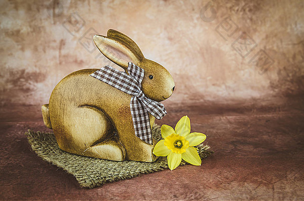 深棕色背景下的棕色复活节兔子和水仙花装饰