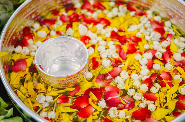 泰国泼水节用的带有泰国香水的水勺，带有五颜六色的花瓣和花环，泰国，盛有茉莉花、玫瑰等花的碗
