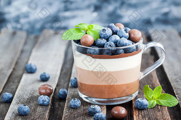 美味的三层巧克力<strong>慕斯</strong>甜点，配以新鲜蓝莓、薄荷和糖果，盛在玻璃杯中