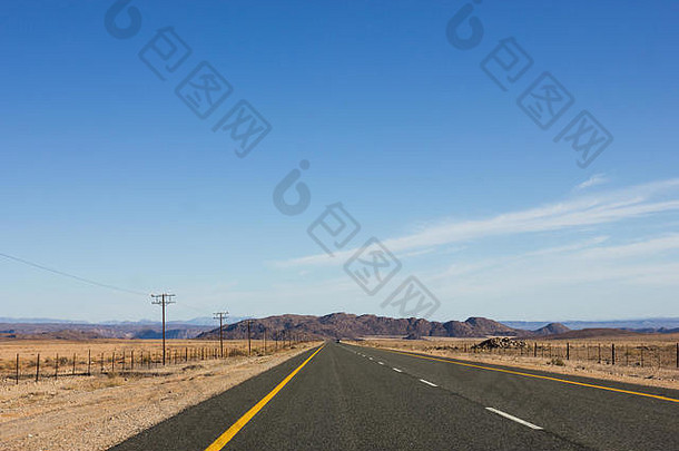 在南非干旱干旱的土地上，一条铺着柏油的长国道在纳米比亚角公路上遥遥领先，一辆车停在前面