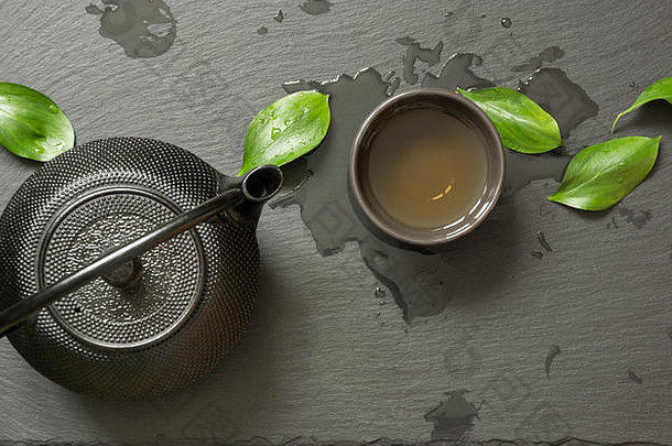 绿色日本茶黑色的板岩背景黑色的茶壶碗绿色茶前视图复制空间