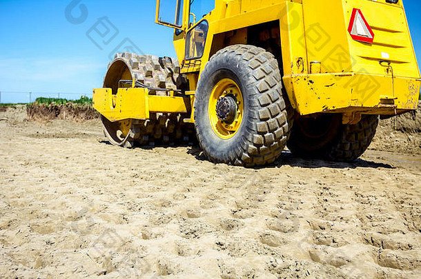 带钉子的巨大压路机正在建筑工地压实土壤、沙子。
