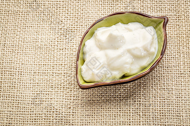 一小碗叶子形状的希腊酸奶，加香草和粗麻布帆布