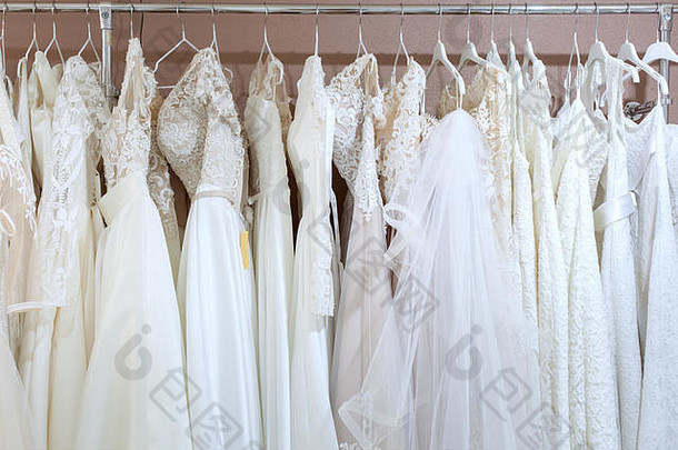 站在新娘沙龙里，穿着许多漂亮的婚纱。