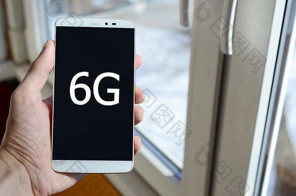 一个人在手里拿着的黑色智能手机显示屏上看到一个白色的铭文。6G。