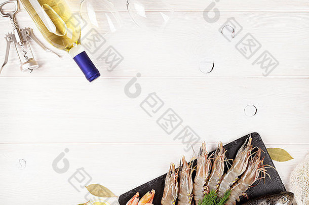 木桌背景上的新鲜生海味、香料和白葡萄酒瓶。具有空间的俯视图