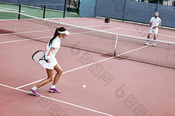 年轻的夫妇白色运动服装玩网球法院在户外