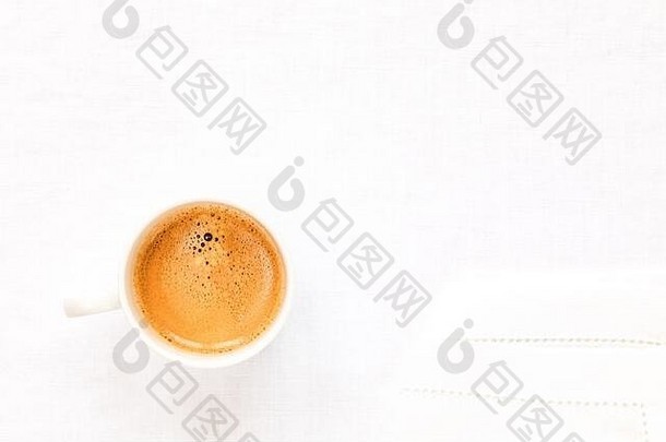 在白色亚麻桌布上放一杯双份浓缩咖啡。这张照片是在正上方拍摄的。