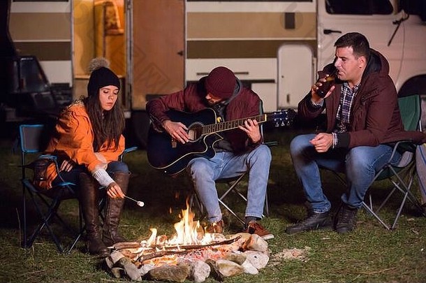 游客们在露营地弹着吉他，烤着棉花糖。复古露营车。在山地露营。