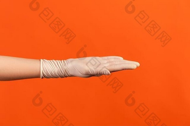 戴白色外科手套的人的手侧面特写图，显示手。室内，工作室拍摄，在橙色背景上隔离。