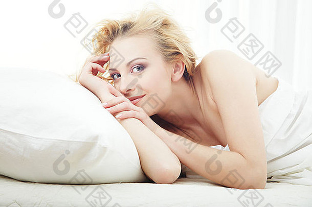早晨，一位微笑的女士躺在床上，娇生惯养