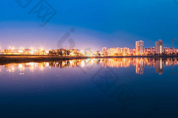 城市居住区全景，在夜晚的照明下俯瞰城市湖泊或河流和公园，反射在水面上。国美的春天