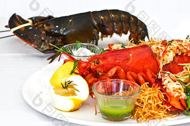 活的和熟的龙虾和蔬菜一起放在白色盘子里。偏远的