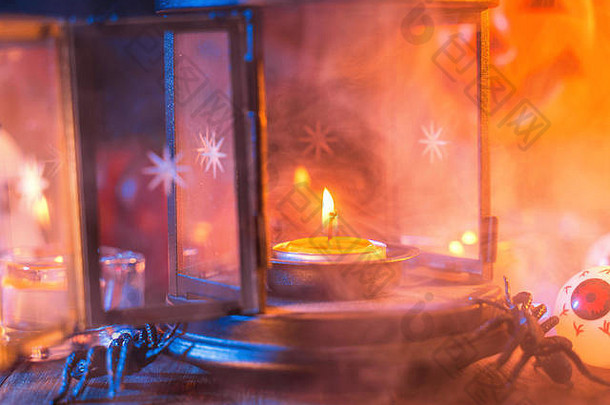 万圣节假期的概念设计南瓜，蜡烛，蓝调烟雾围绕在黑暗的木桌上的怪异装饰，特写镜头。