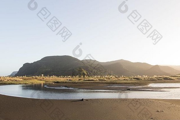 在<strong>新西兰</strong>奥克兰偏远的黑沙滩Whatipu，清晨可以看到海岸河流和灌木覆盖的Waitakere山脉山脉。