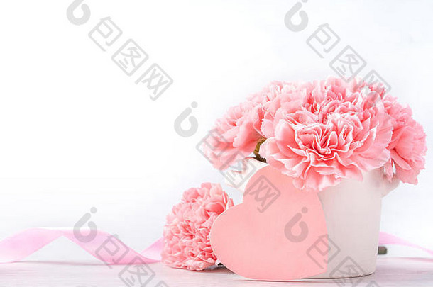在明亮的背景下，白色花瓶中盛开着美丽的婴儿粉色柔嫩康乃馨，五月母亲节问候妈妈，