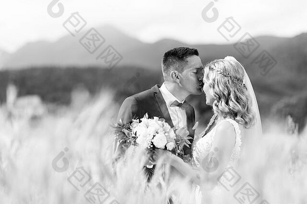 在斯洛文尼亚农村的麦田里，新郎温柔地拥抱新娘，亲吻她的额头。