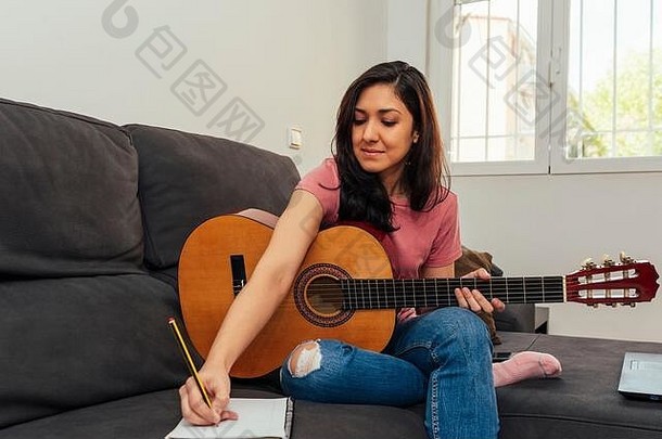 在家的沙发上为吉他作曲的女人