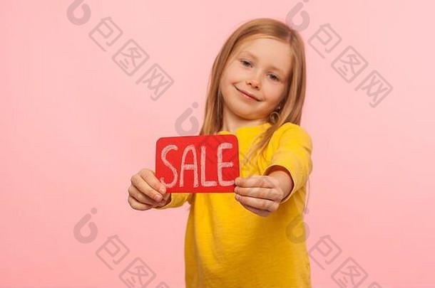 周末打折！黑色星期五，兴奋、可爱、快乐的小女孩在儿童商店展示促销标语，对着镜头微笑，宣传低价。我