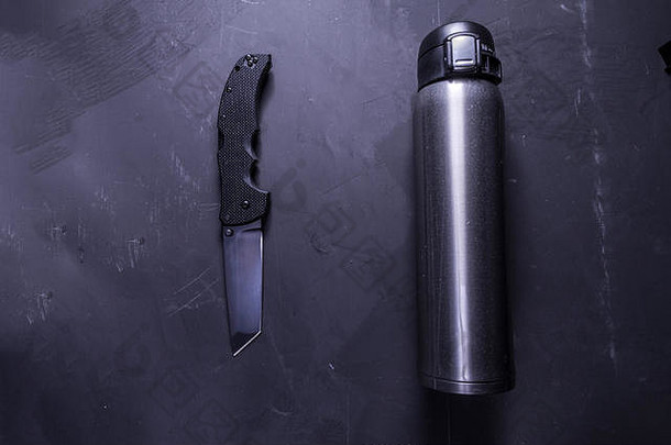 刀和热水瓶。黑色的刀和闪亮的瓶子。平面板条。