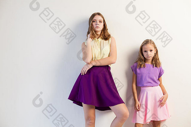 两个穿着彩色衣服的女孩姐妹白色的墙壁