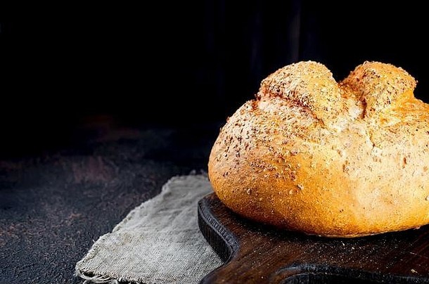 黑木桌上的小麦头新鲜烤面包、低调照片、概念健康食品或食品