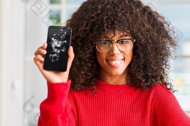 一位非洲裔美国妇女手持破损的智能手机，脸上挂着幸福的表情，脸上露出自信的笑容，露出牙齿