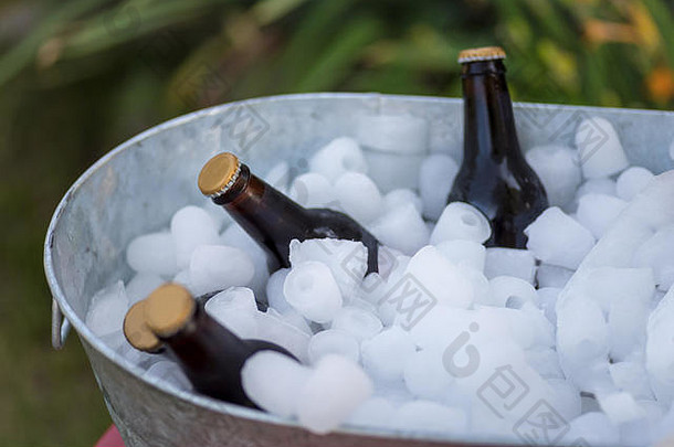 夏日派对上，一瓶瓶啤酒放在装满冰块的镀锌浴缸里