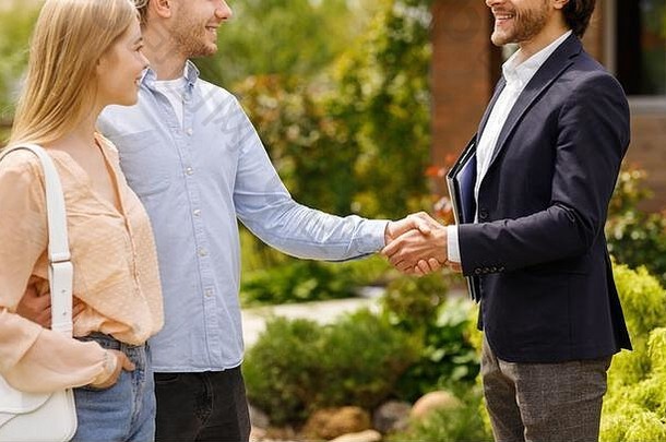 房地产经纪人和他的客户握手，在户外完成<strong>房屋租赁</strong>交易的画面