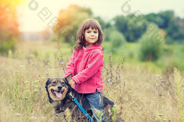 快乐的小女孩和狗在田里散步