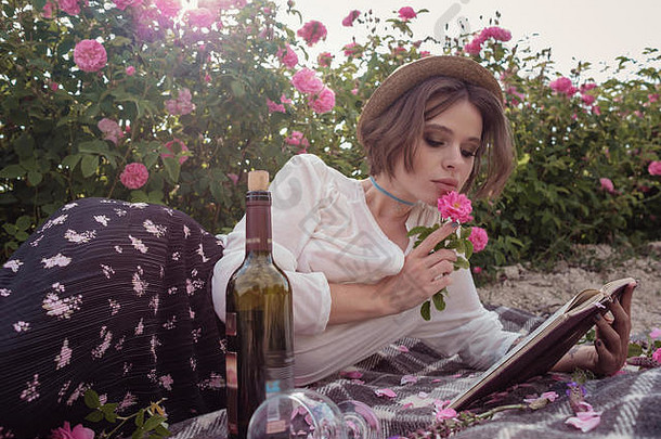 美丽的女孩穿他书坐着草玫瑰街国家女孩享受日落酒阅读书香玫瑰嘎嘎
