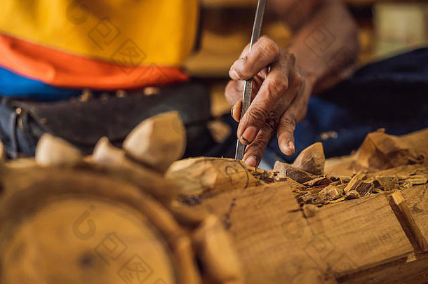 木雕大师用一把特殊的刀制作了一道木制民族菜——一个有图案把手的勺子。他双手特写的一块碎片