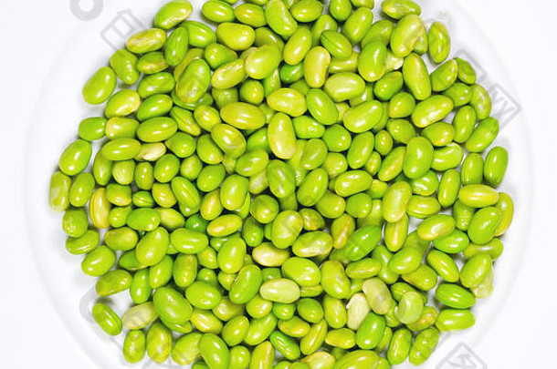 毛豆。白色盘子上的绿色大豆。豆荚外的未熟大豆。大豆，一种豆类，烹饪后食用，蛋白质来源。