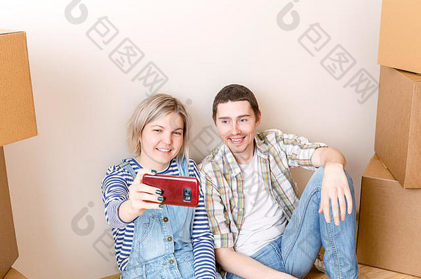 一对年轻夫妇坐在纸板箱中间自拍的<strong>照片</strong>