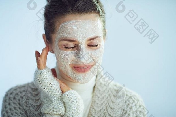 放松现代年女人卷脖子毛衣开襟羊毛衫白色面部面具部分冬天皮肤护理孤立的冬天光蓝色的