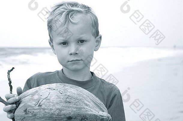 夏威夷海滩上的小男孩手持椰子的黑白照片
